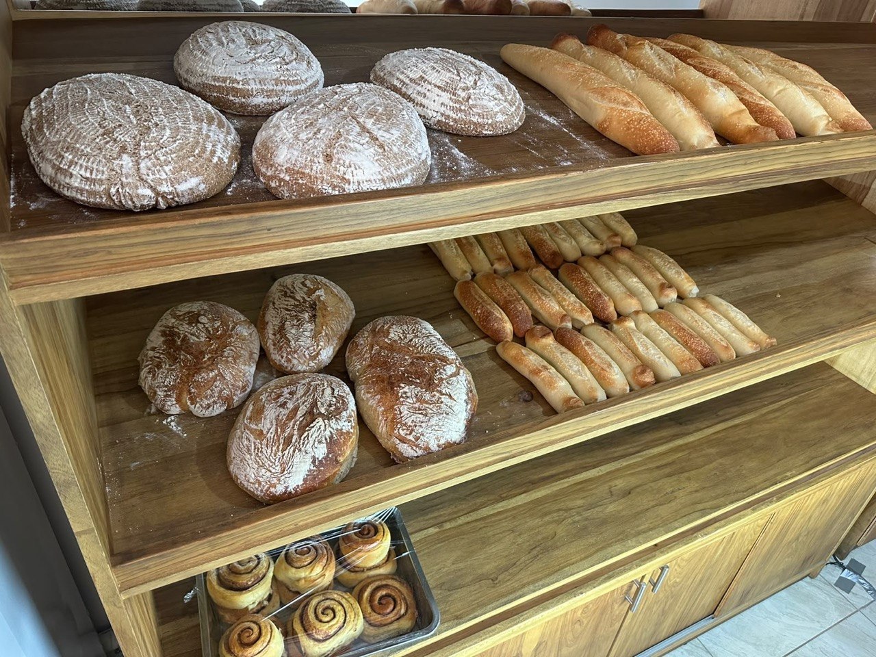 Estantes de la panadería con hogazas, baguettes y rollos de canela