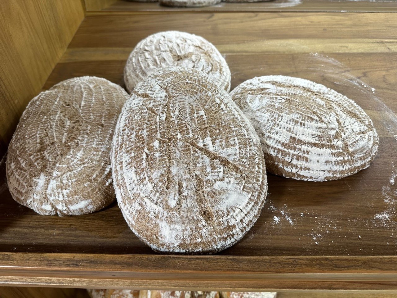 Hogazas rústicas de masa madre enharinadas sobre un estante de madera