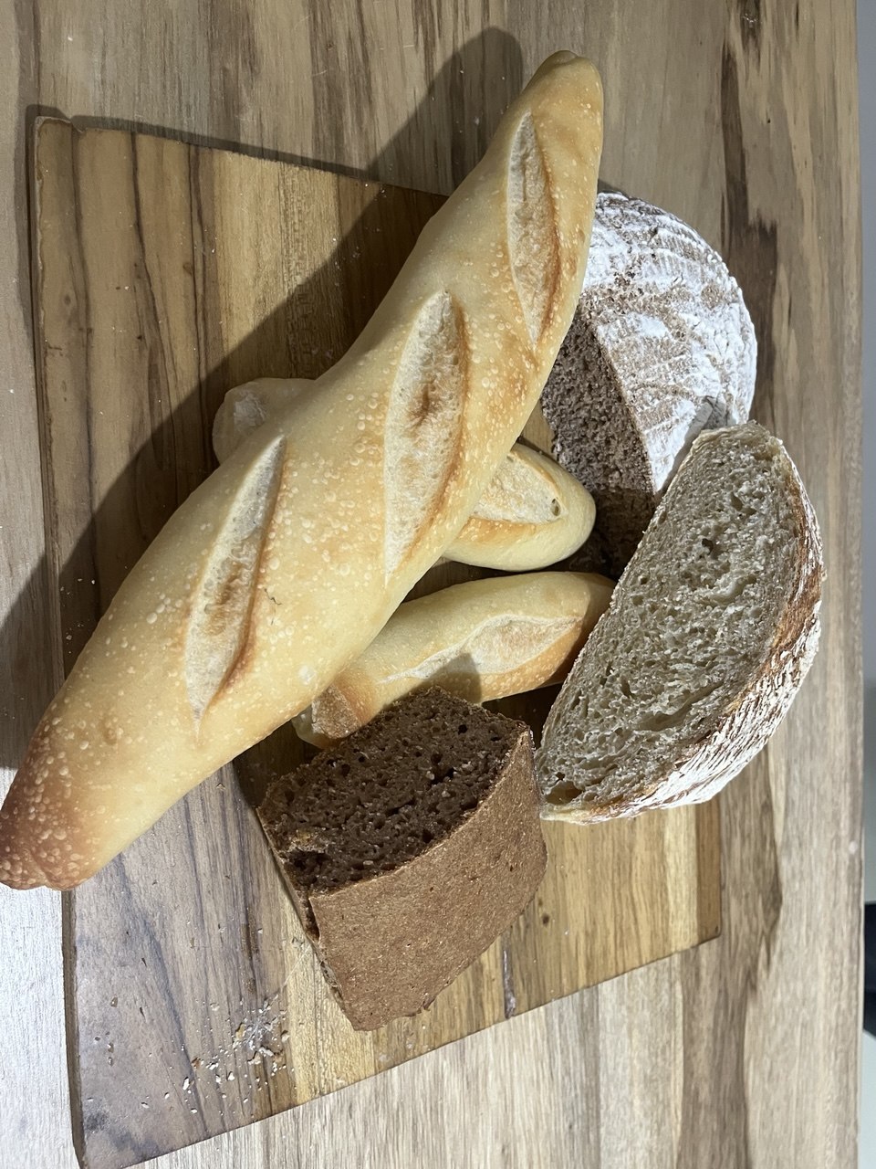 Surtido de baguettes, hogazas y pan rebanado sobre tabla de madera