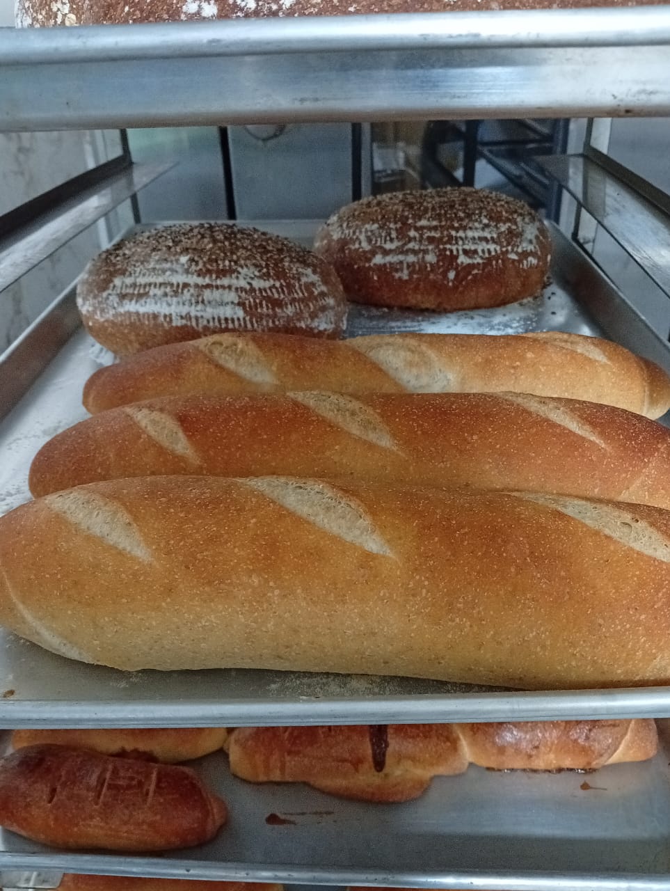 Bandeja con baguettes, hogazas y panes dulces recién horneados