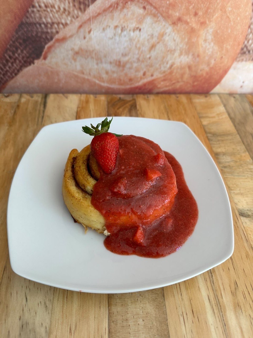Rollo con salsa de fresa y una fresa fresca encima
